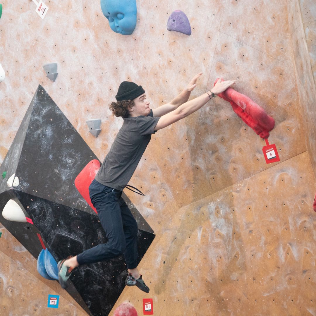 student jumping from hold on indoor climbing wall